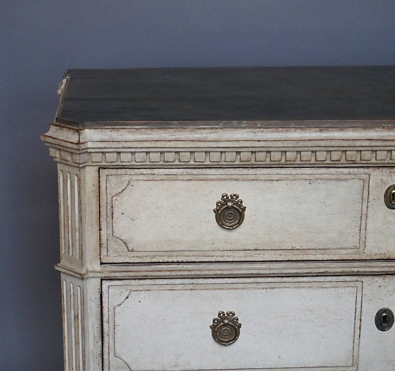Swedish chest of three drawers, circa 1840, with late Gustavian influences. Raised panel drawers, canted corners and dentil molding under the shaped top. Brass pulls and escutcheons.
