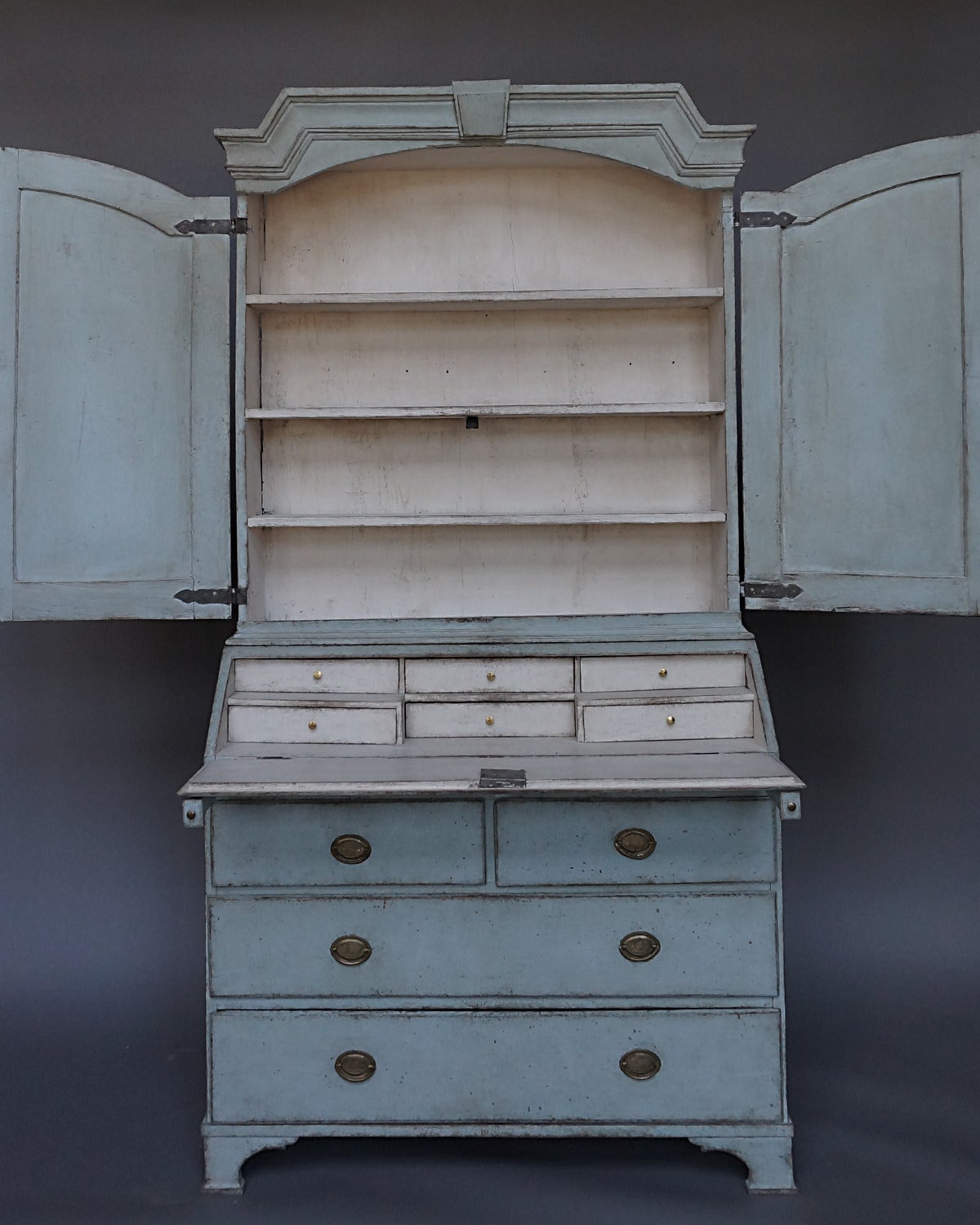 Early Swedish two-part secretary, circa 1820, with a squared cornice with keystone detail over a pair of arched doors with raised and reeded panels. The lower section has a fitted interior behind the slant front and two over two drawers below.