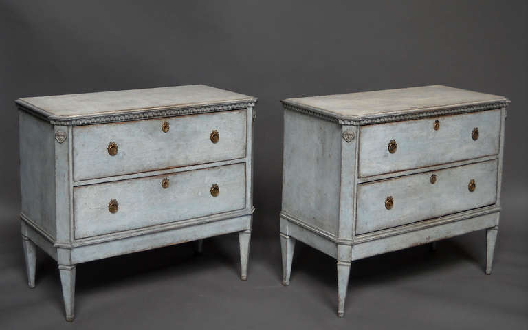 Pair of commodes in the Gustavian style, Sweden circa 1840, in pale blue paint. Canted corners with applied classical heads at the top, and dentil molding under the shaped top.