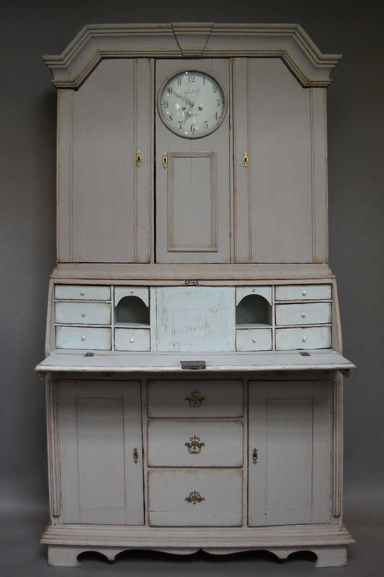 Period Swedish Baroque secretary, circa 1780, with integral Mora clock. Built-in two sections, the upper library has four shelves on either side of the clockworks and an arched cornice.

The clock has a signed enamel dial and retains its original