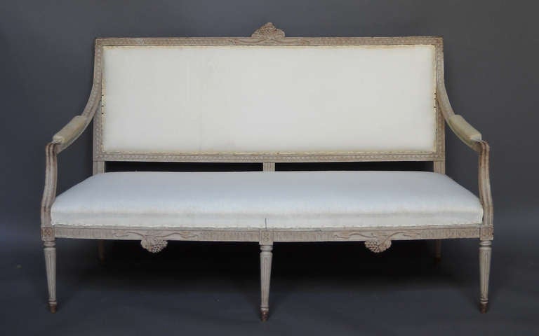 Settee in the Gustavian style, Sweden circa 1900, with egg and dart molding inset with grapevine motifs. Upholstered seat, back, and manchettes. Tapering round legs.