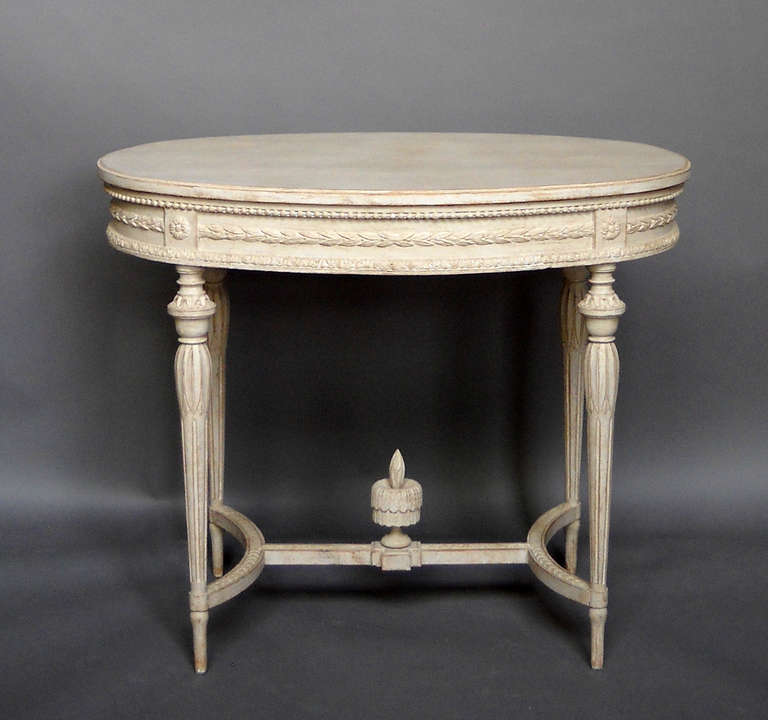 Oval Swedish side table, circa 1910, from a private collection in Stockholm. The apron is carved with beaded molding and laurel swags, and the curved stretcher supports a central carved fountain with flame.