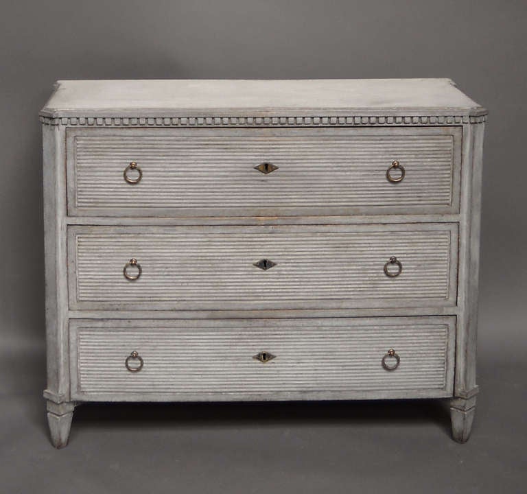 Chest of drawers, Sweden, circa 1840, with drawer fronts carved with reeded recessed panels. Dentil molding around the shaped top and simple ring pulls and lozenge-shaped escutcheons.