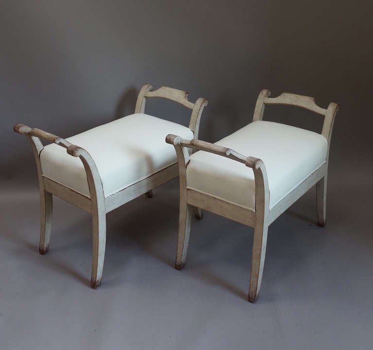 Pair of upholstered benches, Sweden circa 1840,with saber legs extending up into shaped armrests. Simple, elegant style.