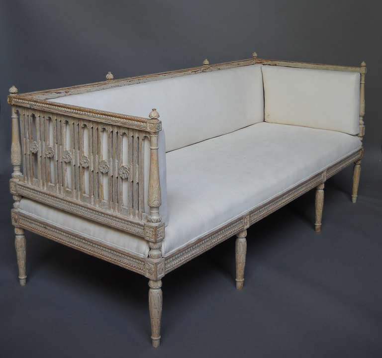 Period Gustavian day bed, Sweden circa, 1770, with carved frame and upholstered seat. The balustered back and sides have repeating carved flowers, with bellflower friezes at the top and bottom. Both the corner posts and the legs are elaborated
