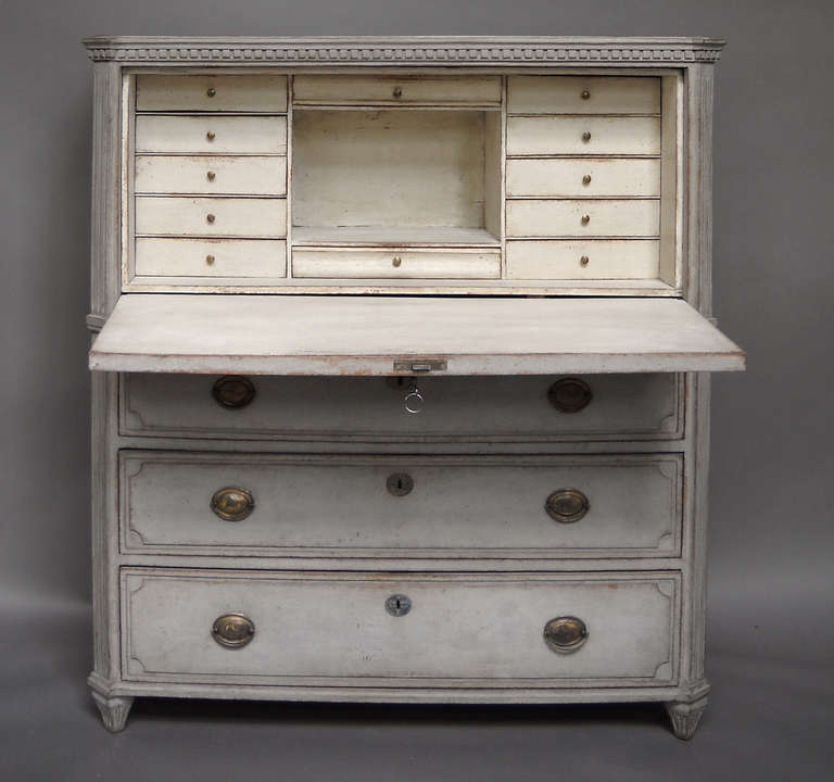 Late Gustavian fall-front secretaire, Sweden circa 1830, with raised panel drawers, a reeded front panel, canted corners, and dentil molding below the shaped top. The fitted interior has a dozen document drawers around a central open compartment.