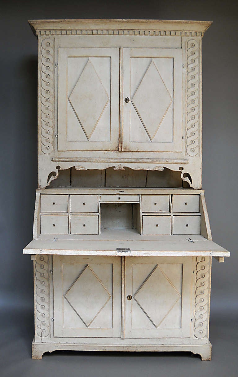 Wonderful rural interpretation of the late Gustavian style in a two part secretary from Ångermanland, Sweden, circa 1820.

The library section has two shelves inside a cabinet with guilloche carving on either side, dentil molding at the top and