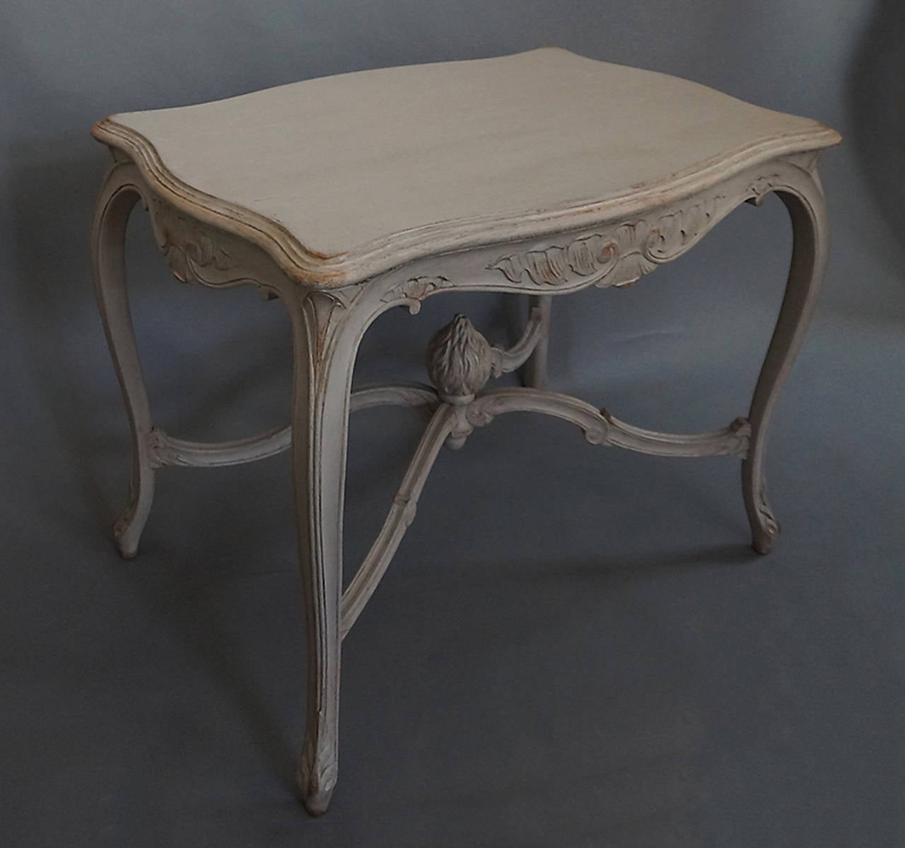 Rococo style center table, Sweden circa 1870, with carved aprons, cabriole legs with foliate detail on the toe and a beautifully carved flame finial where the stretchers meet.