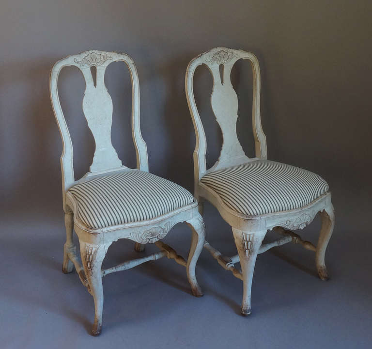 Pair of Swedish side chairs with rocaille carving at the top of the keyhole splat and repeated at the front below the slip seat. Carved rococo legs braced with turned stretchers. Newly upholstered seats.