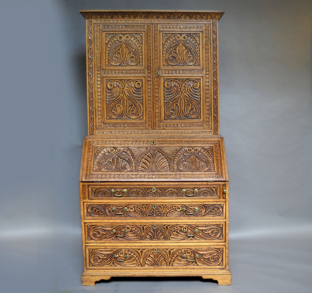 Renaissance style two-part secretary of carved oak, Denmark circa 1880. Four graduated drawers below the writing surface, and two shelves behind double doors above. Carved lozenges decorate either side of the lower section.The richly carved slant