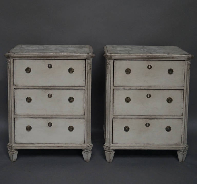 Pair of Swedish three-drawer chests from the late Gustavian period, circa 1830. Marbled tops, canted corners with reeded corner posts, and simple tapered feet.