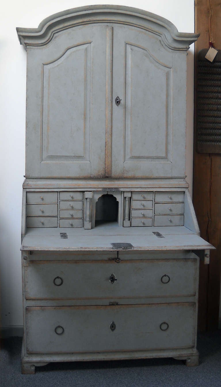 Swedish rococo secretary, circa 1790, with original hardware. Upper library section has three shelves, one notched, behind double doors with raised, arched panels. The lower section has three drawers below the writing surface and a fitted interior