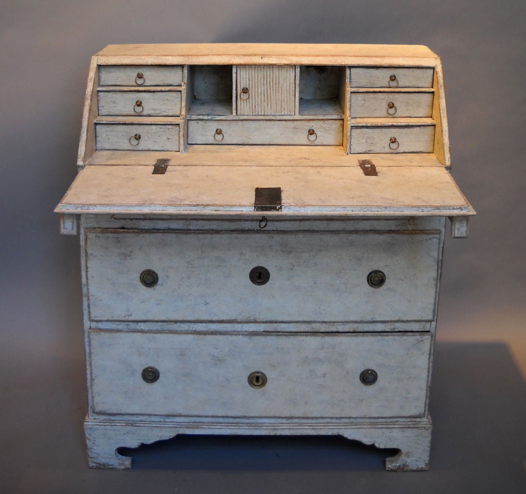 Small Swedish slant-front writing desk, circa 1820. Two full-width and one smaller drawer under the writing surface, all on a shaped bracket base. The interior has seven drawers and three cubbies, one with a reeded door, and with wire ring pulls on