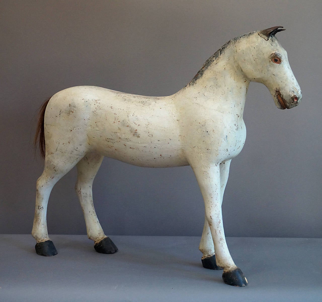 Carved horse, Sweden, circa 1910, in a larger size and having a horsehair tail, painted mane and eyes, and leather ears. There is a small chip in the off fore hoof.