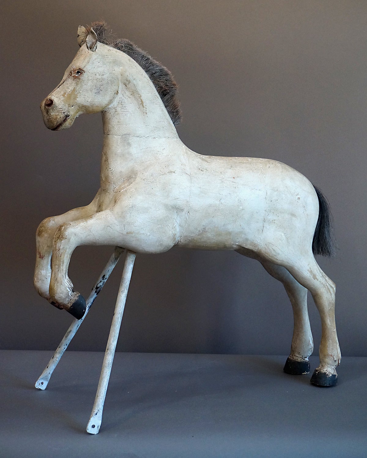 Carved Swedish horse, circa 1910, in a prancing pose and supported by a metal stand. Cropped horsehair mane and tail, leather ears and carved feathering on the fetlocks.