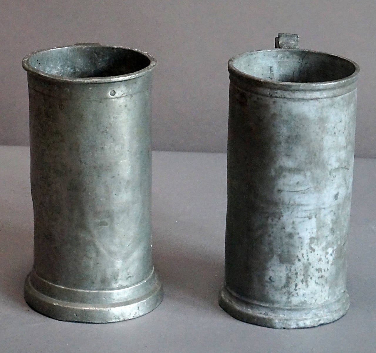 Assembled pair of 1 liter pewter measures, France circa 1820. One has an anchor hallmark and the other is marked with a punched diamond and various punched letters which may indicate date of manufacture.