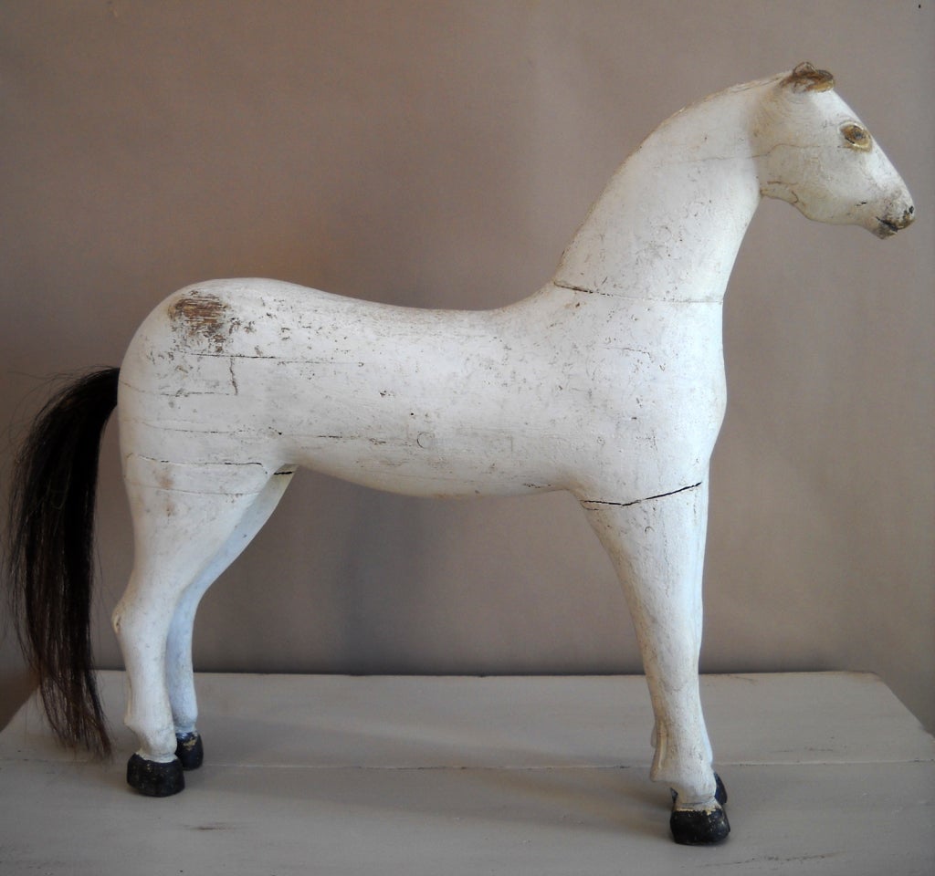 Small toy horse, Sweden circa 1880, with carved ears which have suffered some damage over the years, and painted eyes. The hooves are painted black, and the tail is natural horsehair. The interesting face suggests that he was carved at home by a