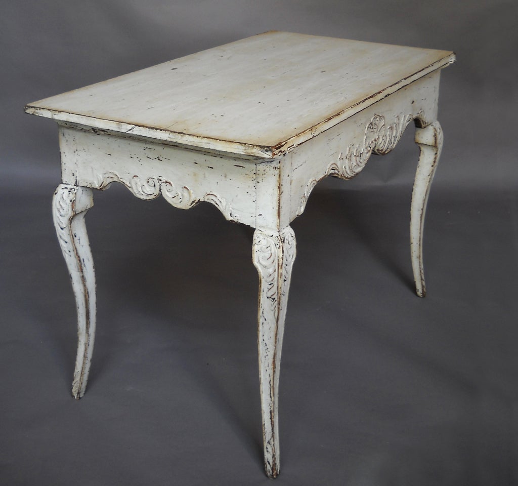 Rococo style side table or writing table with one divided apron drawer, Sweden circa 1860. Tapering cabriole legs with carved knees, and a carved shell motif centering the full-width drawer.