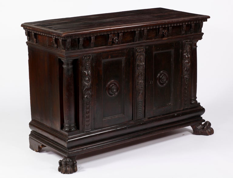An Italian Walnut & Veneer Credenza
18thcentury & later
 
The rectangular moulded top above two short panelled drawers with knob handles, and a pair of doors with rosette-carved handles, flanked by figural supports and column supports, with