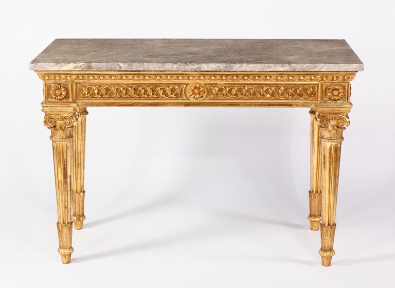 An Important Neoclassical 
Giltwood Console
Roma,Italy 18th Century

The mottled grey rectangular marble above an egg and dart edge, the guilloche frieze with a central rosette, on reeded tapering legs on foliate carved feet and headed by capitals