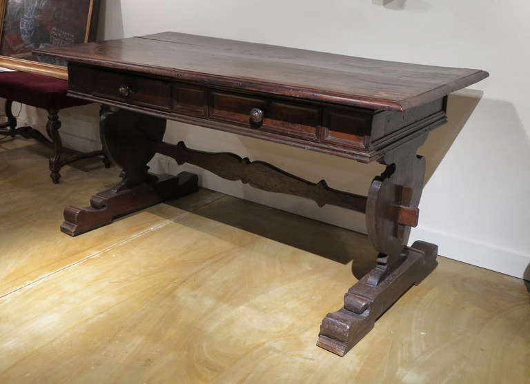 An Italian Walnut Baroque Writing/Center Table
17th Century &  later

The rectangular molded top with inlaid decorations at the corners 
over two drawers all resting on a trestle base.

Height 31 1/2 in.  Width 32 1/2 in.  Lenght 62 in.

Tab128
