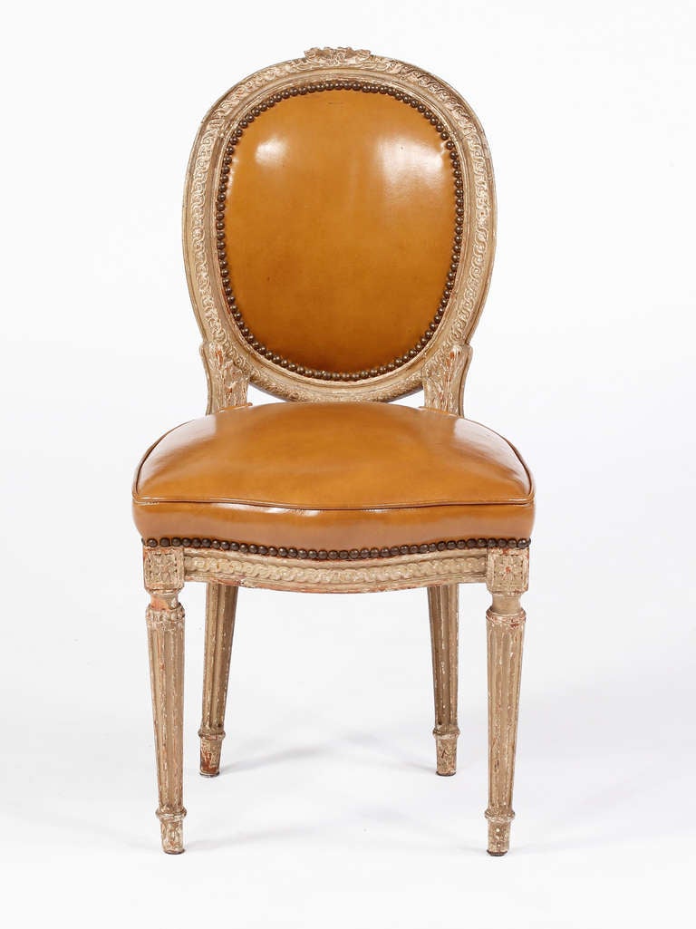 A Set of Louis XVI Painted Side Chairs
Attributed to Claude Sene
18th Century

Jean-Baptiste Claude Sene Maitre 1769

Each oval back with bow-knotted laurel crest, padded leather seat 
above a laurel carved rail, raised on stop fluted