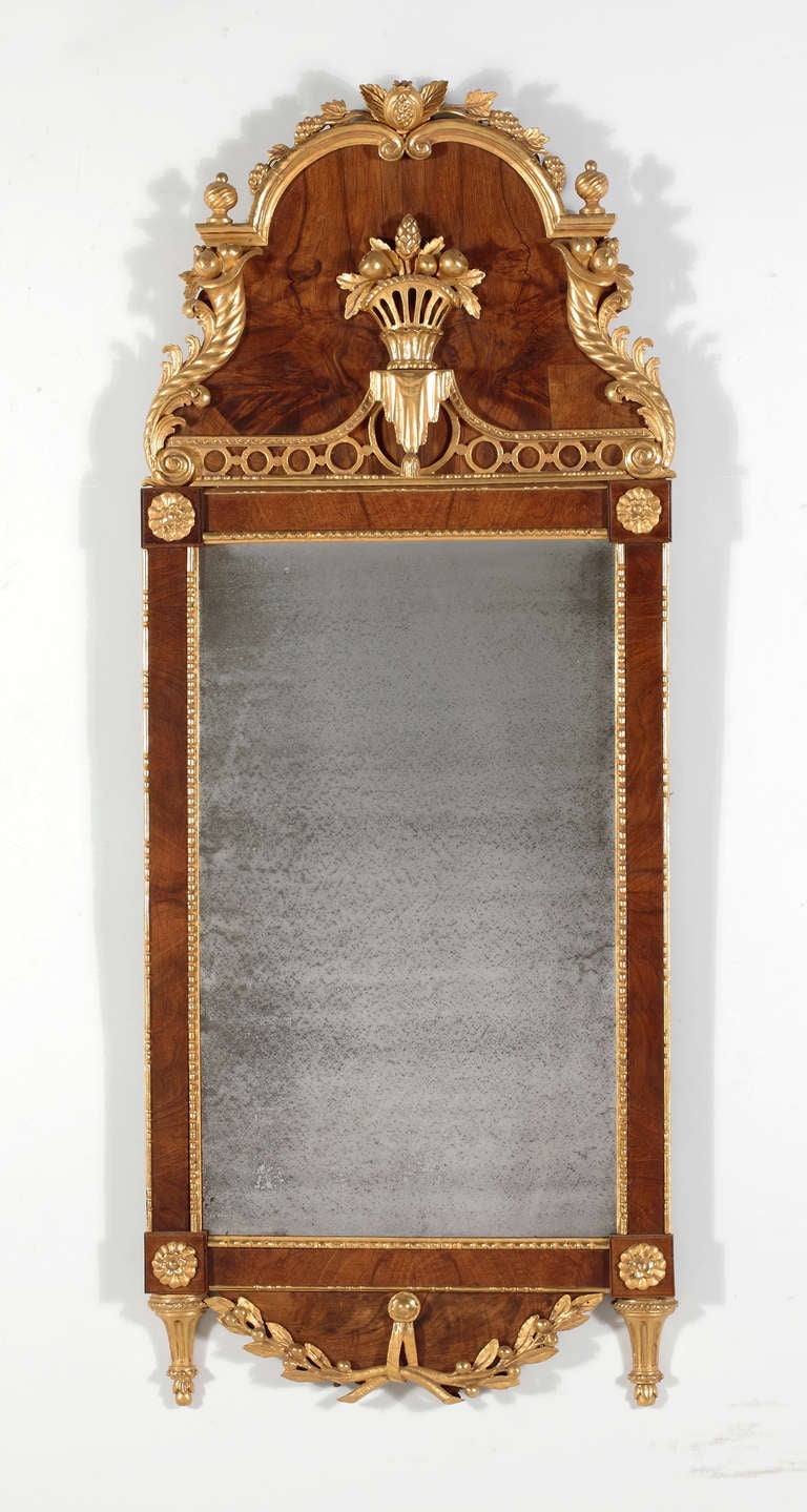 A Fine Baltic Walnut & Parcel Gilt Mirror
Late 18th Century

The cresting with a fruit filled basket flanked by cornucopia; the base applied with laurel leaf swags.

Height 53 in.   Width 21 in.

Provenance:
Private Collection New York;
Le