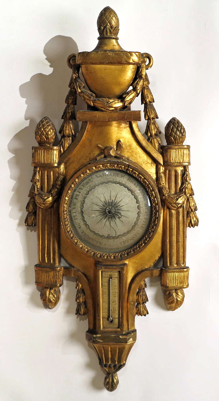 A Fine Louis XVI Giltwood Barometer
French, 18th Century

The classical urn with a finial with down swooping floweral swags 
with two fluted pillars with finial and swags flanking each side of the barometer.

Height 40 in.  Width 19