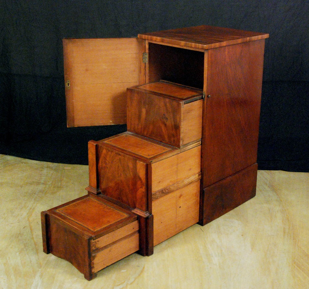 The rectangular top above a conforming pedestal case with a central door enclosing steps over two pull-out step platforms<br />
<br />
H. 37 in. W. 17 in. D. 21 in. <br />
When open Depth 46 1/2 in.