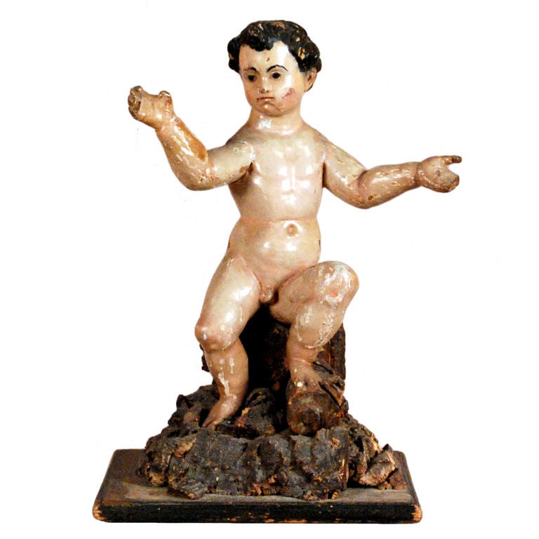 An Italian Carved Polychrome Figure of a Putto Sitting on a Rock