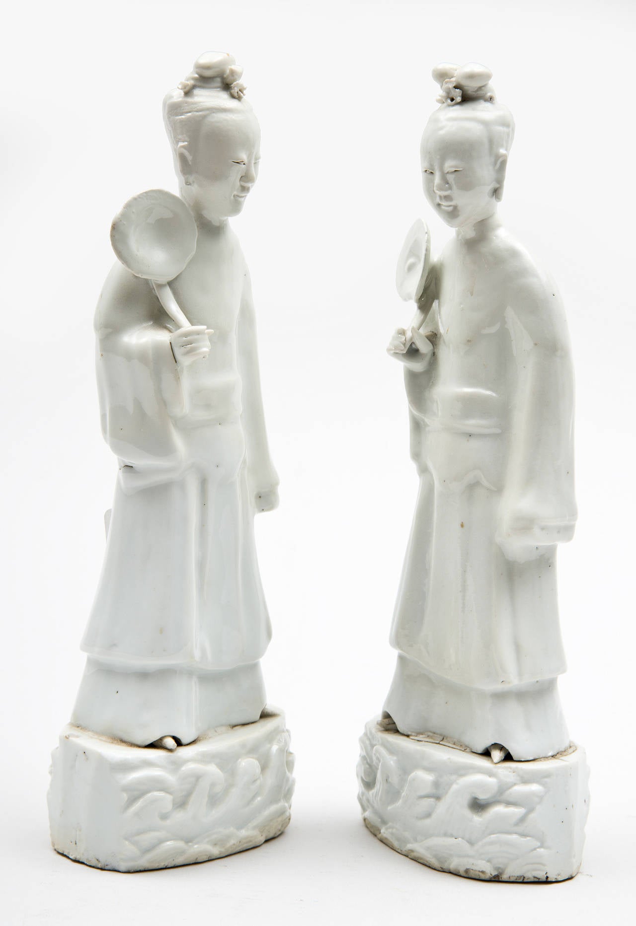 Chinese pair of blanc de chine porcelain female figures, possibly of Quan Yin, holding an open flower and wearing long robes standing on a base of waves of pond water. Some restoration.

Item #6332.