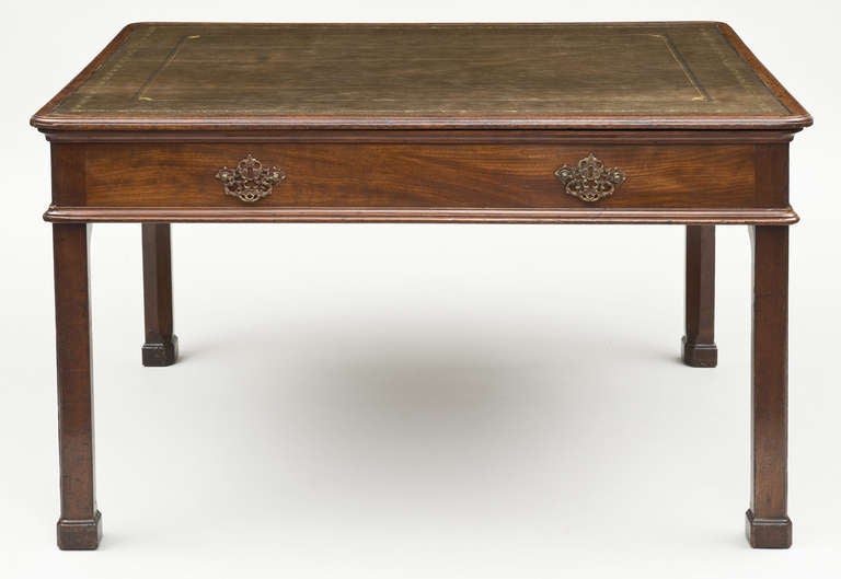 George II period mahogany partners writing table with olive green gilt-tooled writing surface, molded top and bottom edge, side opening drawers with unusual original pierced brass hardware, raised on straight molded chamfered legs ending in