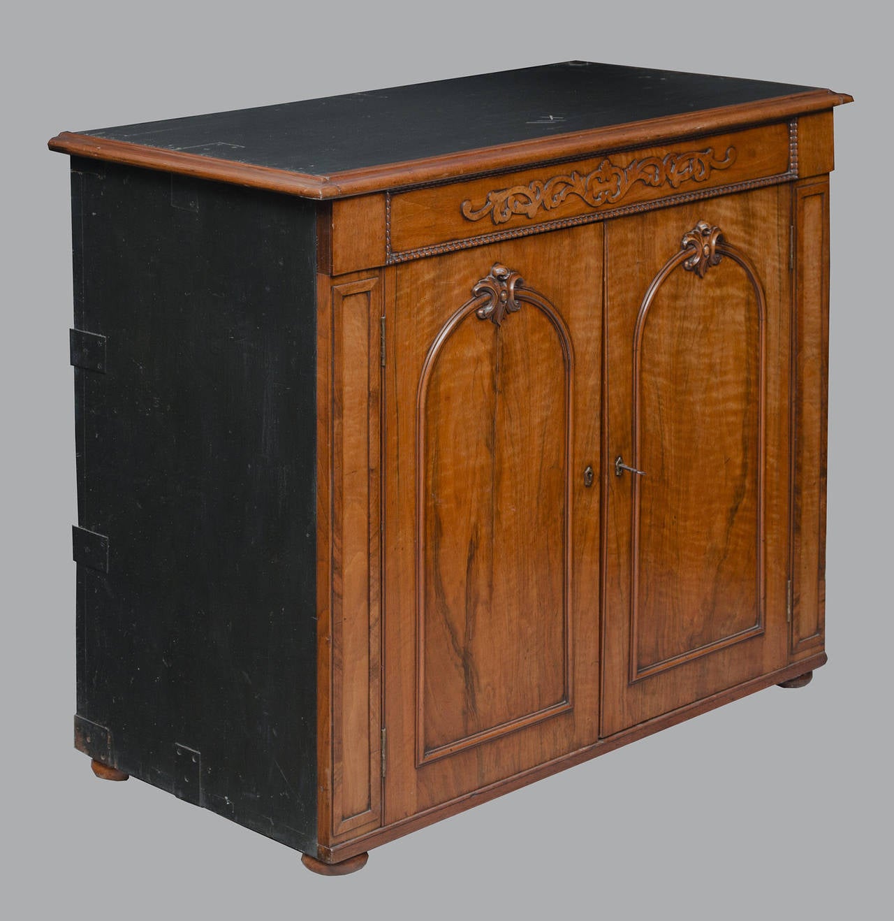 The cabinet has two doors opening to reveal an interior with one shelf, applied molding on frieze surrounded by beading, doors with applied arched molding and carved elements at the top of the arch, raised on bun feet. Sides and top are ebonized