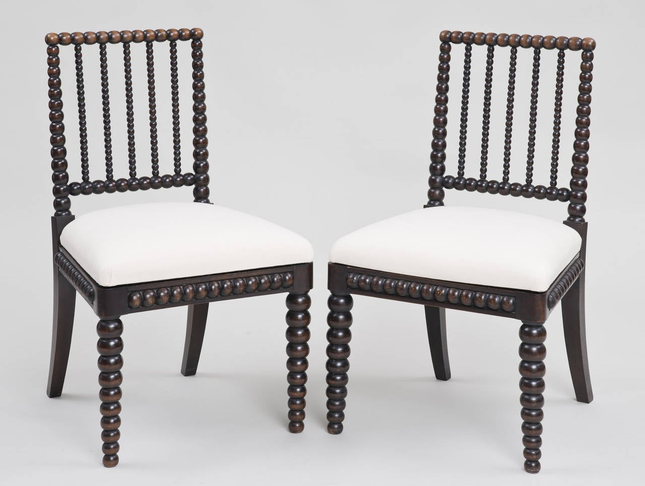 Pair of Regency ebonized bobbin-turned side chairs with lovely faded patina on the top rail, bobbin-turning also on the apron, upholstered removable seats in heavy white cotton fabric.

Item #7364.