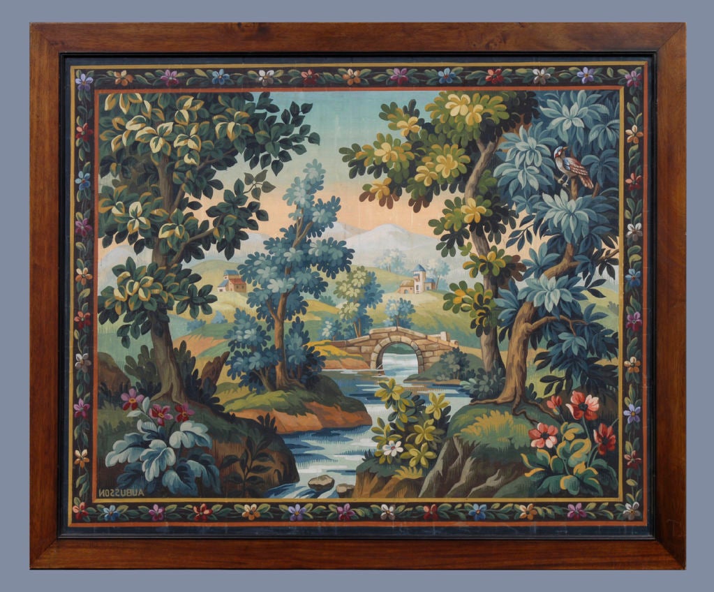French Aubusson verdure tapestry cartoon, gouache on paper, in a mahogany frame with an ebonized inner molding, depicting charming country scene of woodlands, river, bridge, a chateau and mountains in the background with bold trees, foliage and