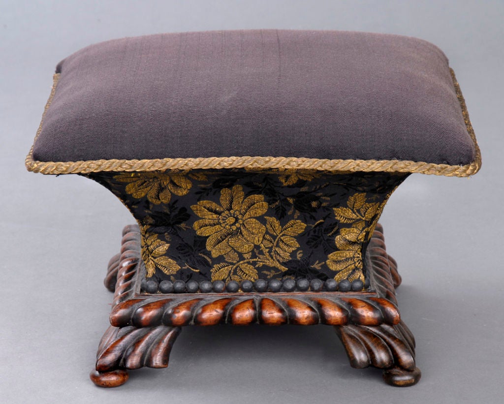 Regency mahogany ladies concave -shaped footstool with carved gadrooned base with similarly carved legs on bun feet, upholstered in horsehair and gold threaded brocade fabric from the waistcoat of Count St. Andyrs.