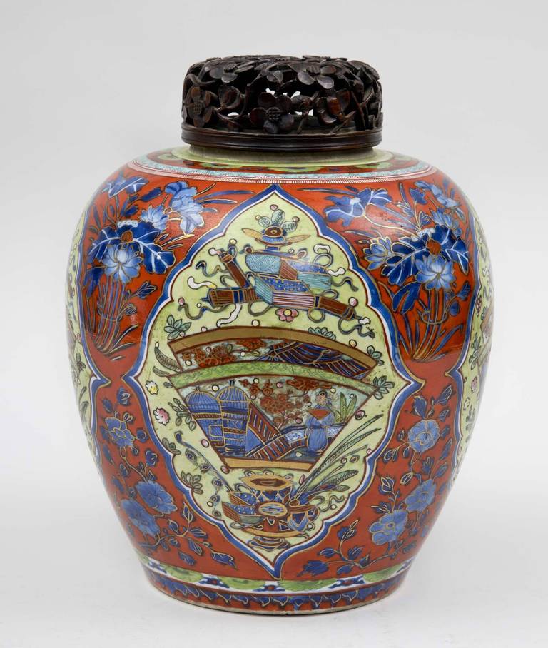 Rare and refined blue and white Kangxi “clobbered” jar with carved lid, very finely painted and parcel gilded in iron red, cobalt blue and poison green, decorated with four shield shapes within which is a figure crossing a bridge with pagodas in the