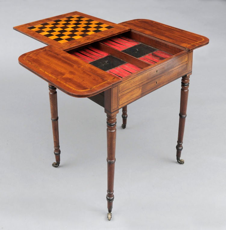 Late Regency mahogany games table with two flaps, the top inlaid with a band of rosewood, the central sliding top revealing a leather backgammon board and reversing to an inlaid chessboard of ebony and satinwood above a frieze drawer fitted for