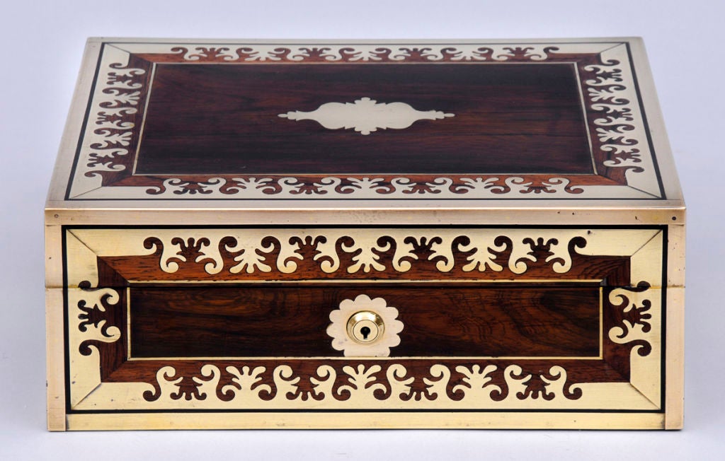 Regency rosewood jewelry box inlaid with unusual foliate shaped brass banding, brass recessed campaign side handles, hinged top opens to reveal dark blue leather interior with two layers of trays with small compartments, mirror concealed behind