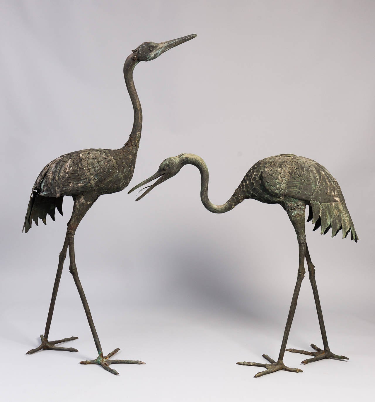 Pair of large Japanese Meiji period cast bronze red-crowned cranes (Tancho) rendered in high relief. There is some loss to the back tail feathers of the tall crane.  Cranes are symbols of peace, longevity and fortune.
Dimensions:
Tall: 65