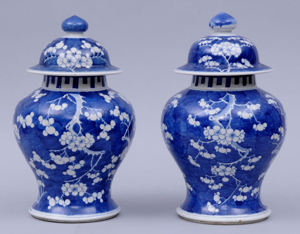 Pair of Chinese blue and white porcelain baluster-shaped lidded vases decorated with flowering prunus branches on crackle ice ground.