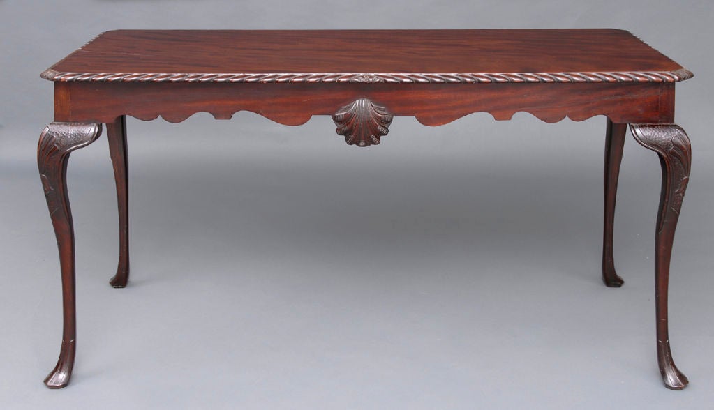 Irish mahogany side table with deeply carved gadrooned top edge, scalloped frieze with carved shell, cabriole legs with carved shell and stars on the knees, ending in elegant intaglio-carved slipper feet.