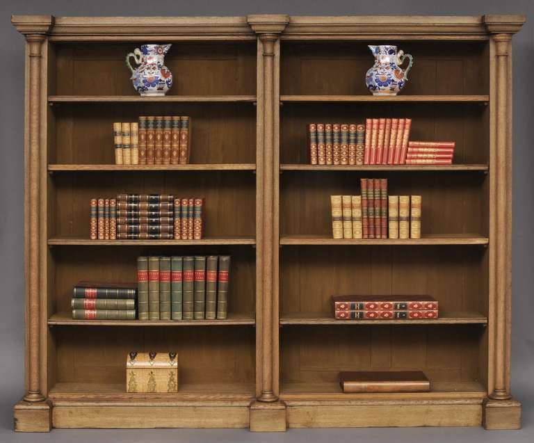William IV bleached oak library open bookcase with breakfront molded cornice, the two sections each with four adjustable shelves, divided by three projecting columns, raised on plinth base.  

Item #6833