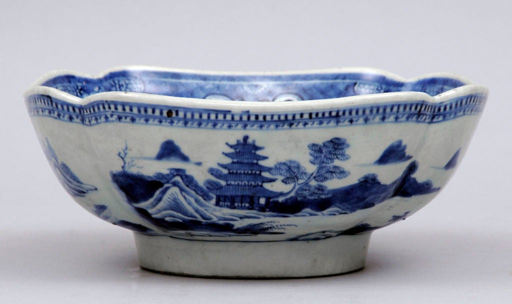 Chinese Canton export blue and white porcelain cut-corner salad bowl. Decoration on outside of bowl is of pagodas, mountain scenery, water, trees and figures.  The inside bottom has a village scene with rockery and a boat with figure.  The inside