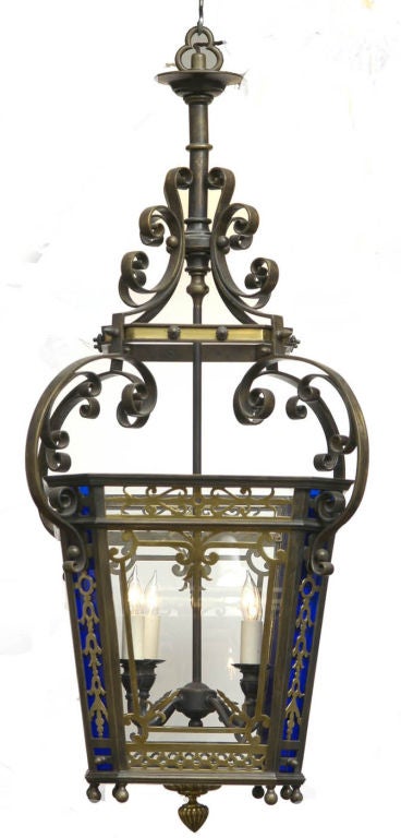 Victorian gilded bronze four-light hanging lantern with canted corners that are decorated with panels of cobalt-colored glass, hung by a series of C-scrolls, acorn-shaped drop finial at bottom. Completely rewired.