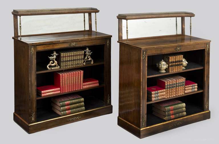 Boldly figured rosewood open bookcases with rosewood cross-banding and satinwood edging around the top, the tiered top shelf with brass pierced gallery on three sides and turned brass column supports above mirrored back panels, two adjustable