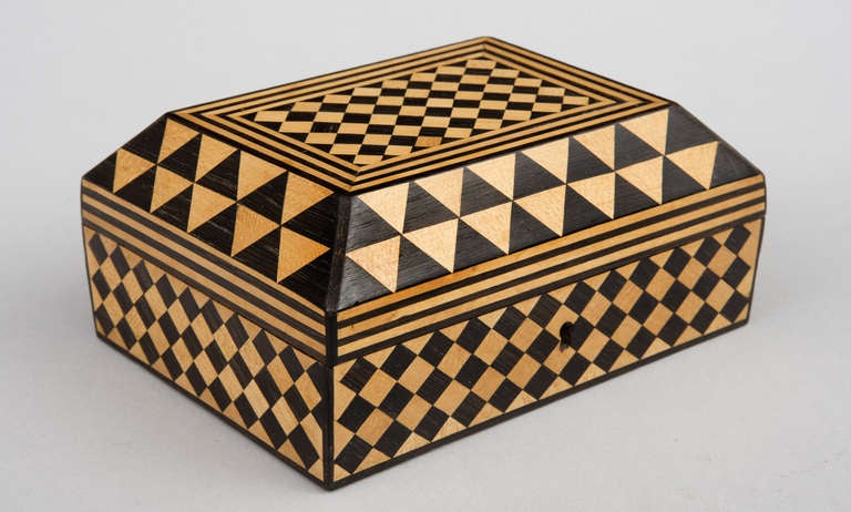A George II period satinwood and ebonized parquetry sarcophagus form box with hinged lid, tapering sides, geometric shapes of diamonds, triangles and stripes. The interior is lined in the original pale pink cotton fabric.

 Measures: Height 3