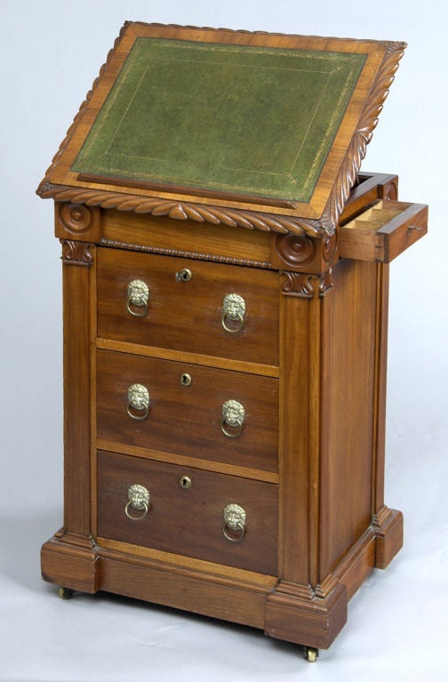 This unusual mahogany cabinet/desk has an adjustable lift-top writing slope with carved gadrooned edge, green gilt-tooled inset leather with removable reading ledge. The carved and beaded frieze has three drawers below with replaced handles. The