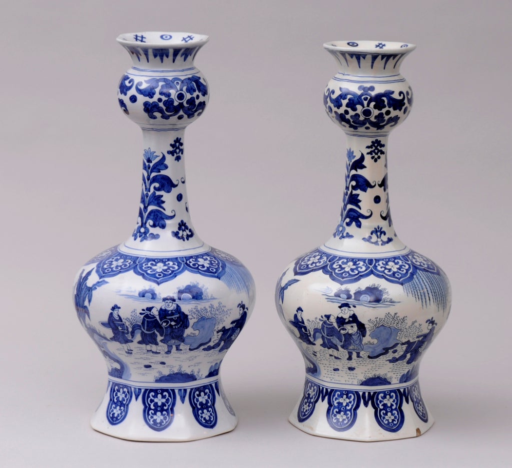 Pair of Dutch Delft blue and white onion bulb vases decorated with
Chinese and European figures, horses, trees and hollow rocks, bordered with stylized flowers and foliage.