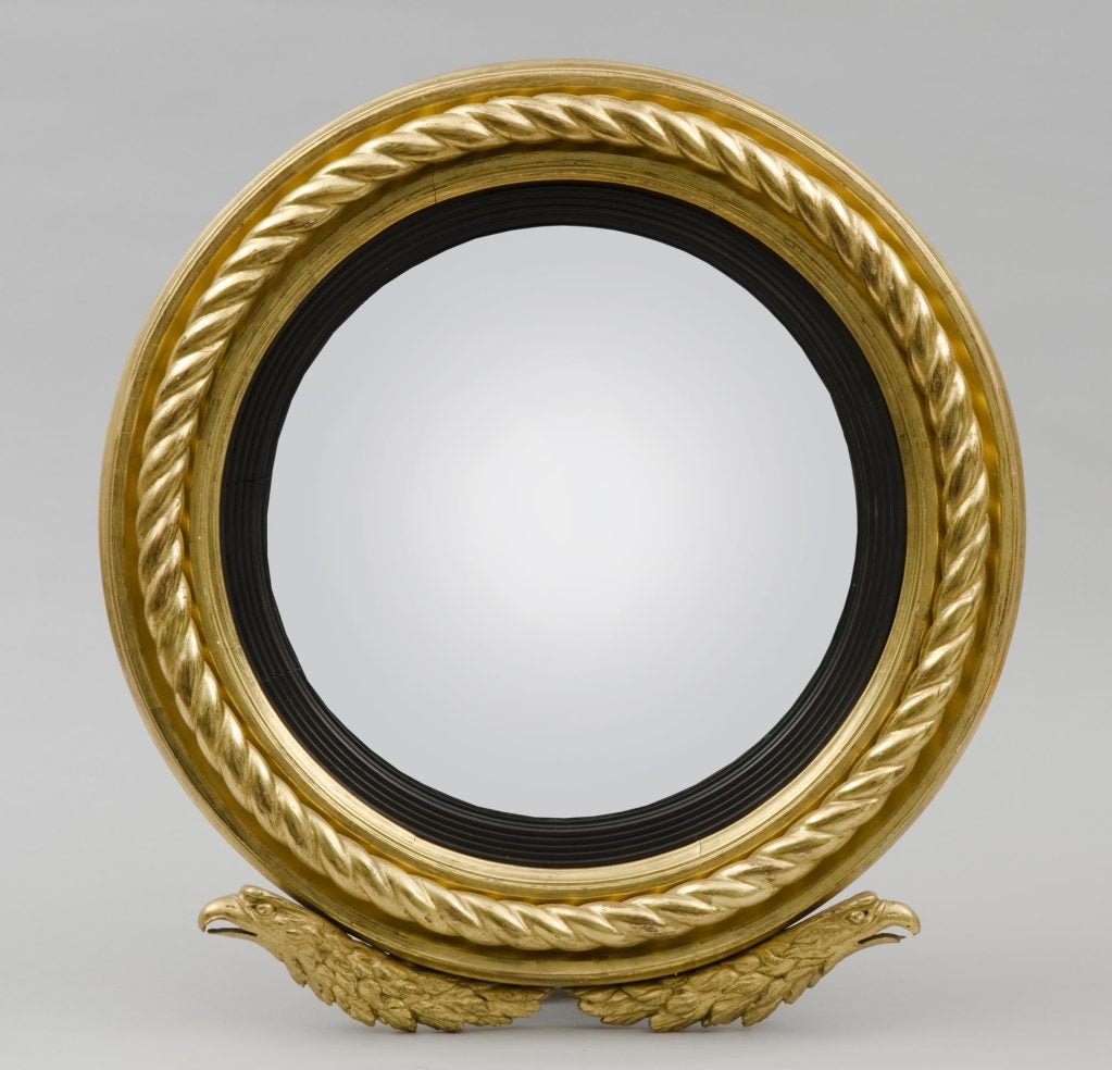 Regency giltwood convex mirror with twisted rope surround, eagle head undermount, ebonized reeded slip.